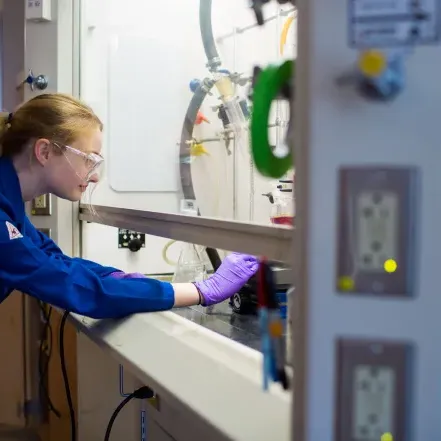 A student working in a lab, wearing safety goggles.